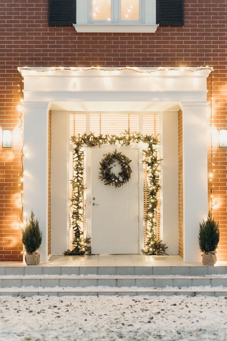 Front entrance with lit garland and wreath